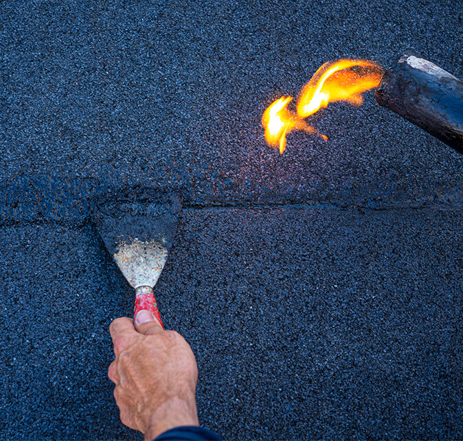 Close-up of a technician troweling and heat-sealing a flat roof membrane seam