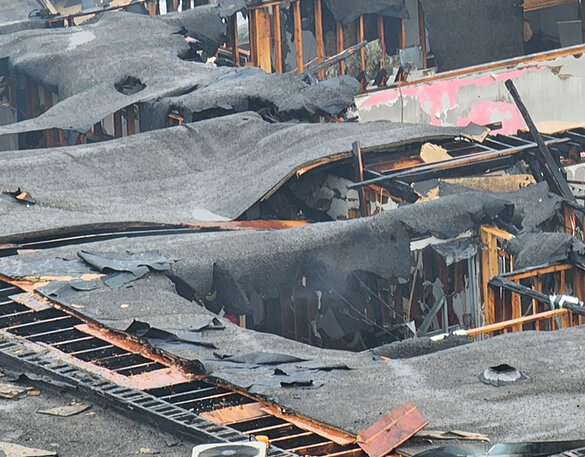Aerial view of a commercial roof with severe fire damage and collapsed framing