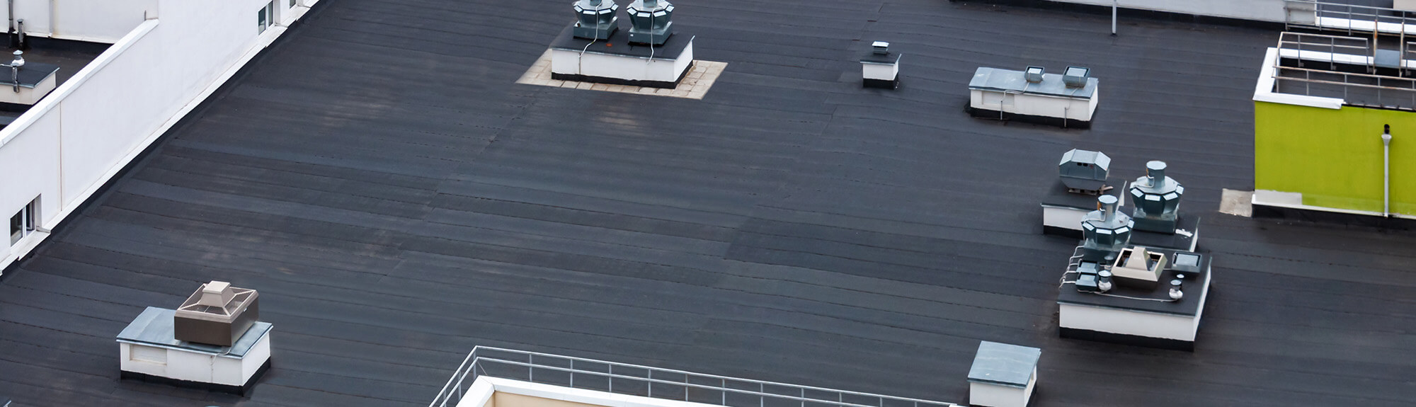 Aerial view of a dark commercial flat roof with HVAC vents and rooftop equipment
